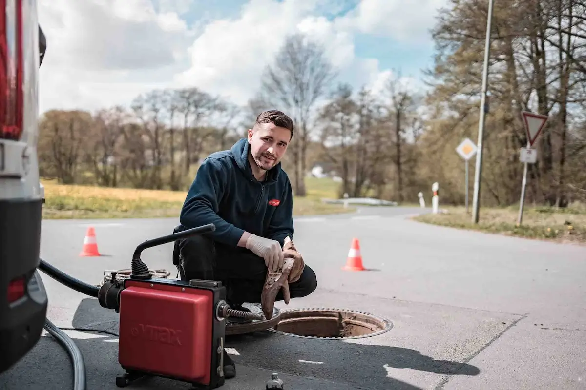 Fachmann bei der Kanalreinigung Esslingen öffnet Straßenkanaldeckel.