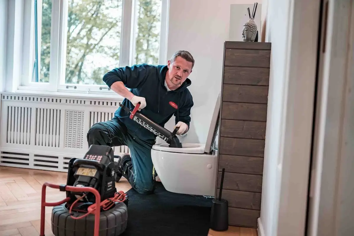 Fachmann bei der Kanalreinigung Lauf arbeitet an Toilette – professioneller Service.